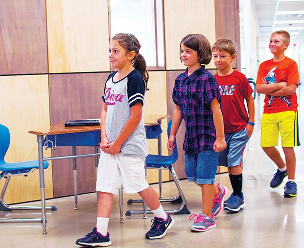 Anna Williams, from left, Danielle Keith, Brayden Mooney and Joshua Fultz walk in single file down the hallway of the second floor of Clinton’s kindergarten-through-third-grade school. The district received a $650,000 grant from the Arkansas Department of Education to continue tutoring before school and enrichment activities after school in kindergarten through the sixth grade. The programs will begin after Labor Day.