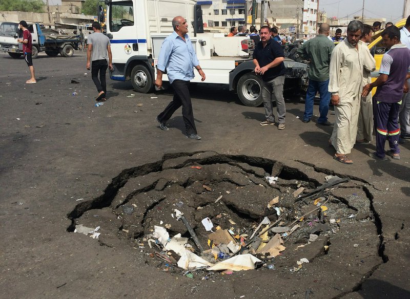 Civilians inspect a crater caused by a car bomb explosion in commercial area of New Baghdad, Iraq, on Tuesday, Aug. 26, 2014. The parked car bomb exploded on Tuesday in a busy area in eastern Baghdad, killing and wounding scores of people, officials said, the latest in a series of attacks to shake the Iraqi capital as the Shiite-led government struggles to dislodge Sunni militants from areas in the country's west and north. 