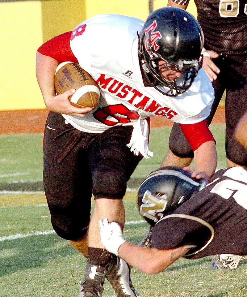 RICK PECK MCDONALD COUNTY PRESS McDonald County quarterback Jake Wood pushes Neosho&#8217;s Montana Duncan to the ground for a short gain during the Mustangs&#8217; 50-0 loss Friday night at Neosho High School.