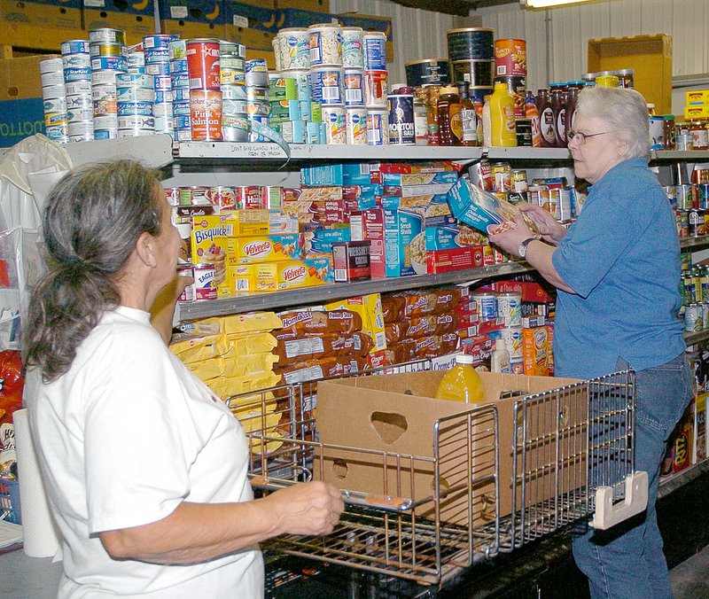 RICK PECK MCDONALD COUNTY PRESS McDonald County Crosslines workers Mary McCaine (left), of Noel and Karen Bowman, of Anderson fill a basket Tuesday morning for a client at the Anderson food pantry.