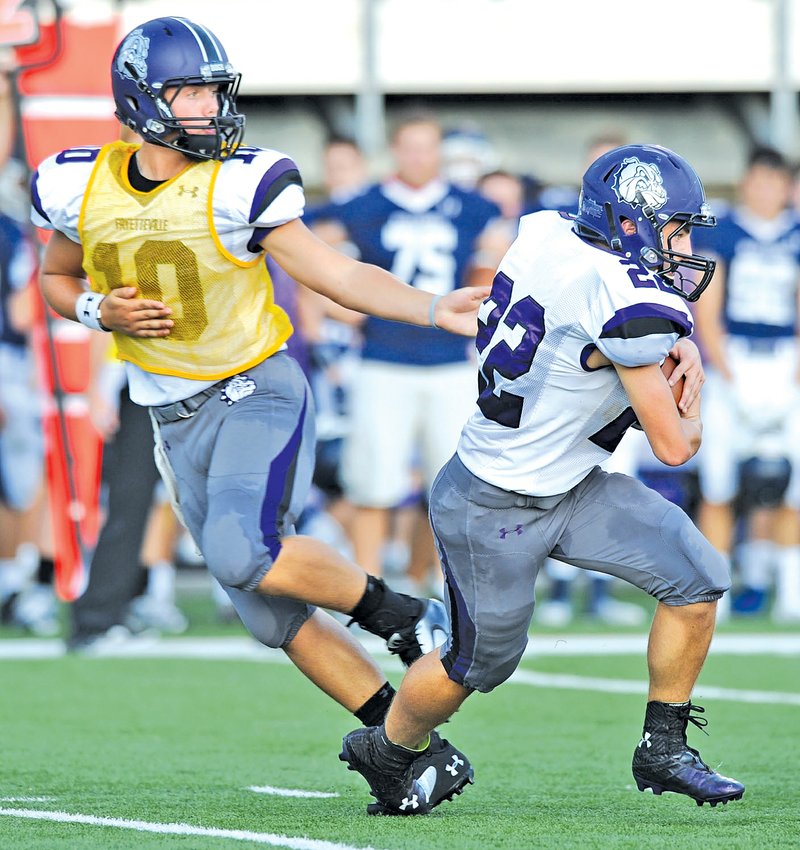  STAFF PHOTO ANDY SHUPE Taylor Powell, Fayetteville quarterback, hands the ball off to running back Luke Rapert against Greenwood during the first half Monday at Harmon Stadium in Fayetteville. Visit photos.nwaonline.com to see more photographs from the scrimmage.