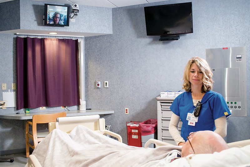 Registered nurse Kristy Wood and volunteer Donnie Clay demonstrate using the video link connecting a patient room at White County Medical Center in Searcy with eICU critical-care specialists in Little Rock.