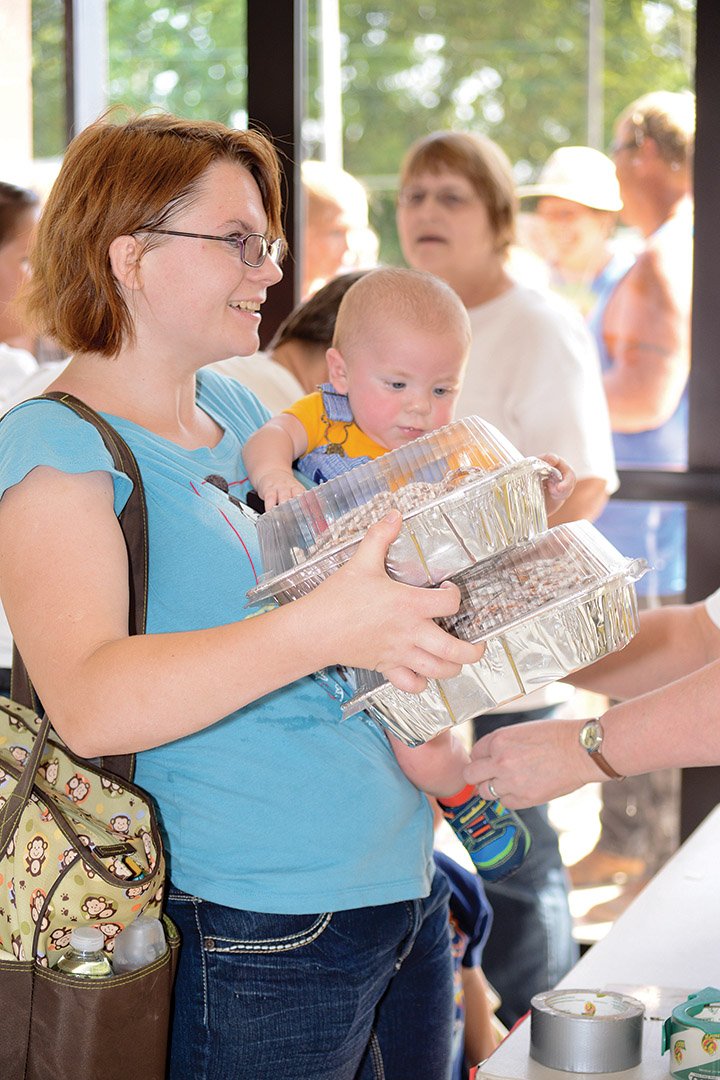 Tabitha Galbraith of Clinton holds little Corbyn Galbraith, 7 months old, while he gets an armband around his ankle during the World Records Largest Potluck Party on Aug. 23 in Clinton.