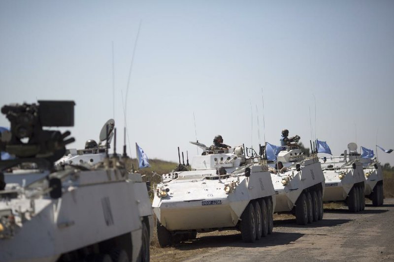 Armored vehicles from peacekeepers of the United Nations Disengagement Observer Force wait to cross Thursday from the Israeli-controlled Golan Heights to Syria.