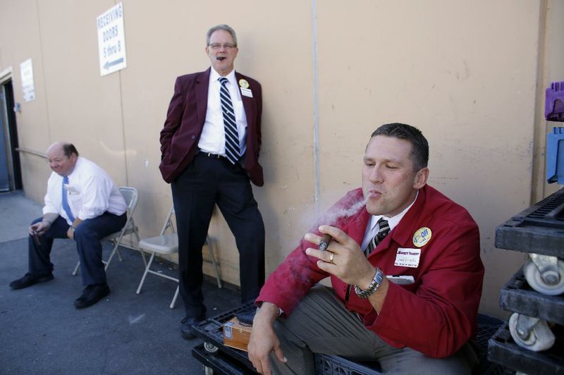 Market Basket employees, from the left, Bob Chausse, of Dracut, Mass., Kevin Feole, of Methuen, Mass., and Jamie Cunneen, of Haverhill, Mass., smoke what Feole described as "victory cigars," behind a Market Basket supermarket location, Thursday, Aug. 28, 2014, in Chelsea, Mass. A six-week standoff between thousands of employees of the New England supermarket chain and management has ended with the news that beloved former CEO Arthur T. Demoulas is back in control after buying the entire company. (AP Photo/Steven Senne)