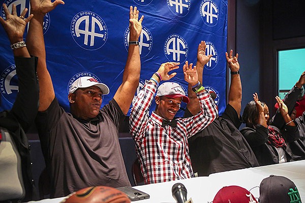 North Little Rock receiver K.J. Hill, center, plaid, , calls the Hogs with his step-father Montez Peterson, left, father Keith Hill, right, and other family members after announcing Friday his oral commitment to Arkansas during a news conference at the Arkansas Sports Hall of Fame in North Little Rock.