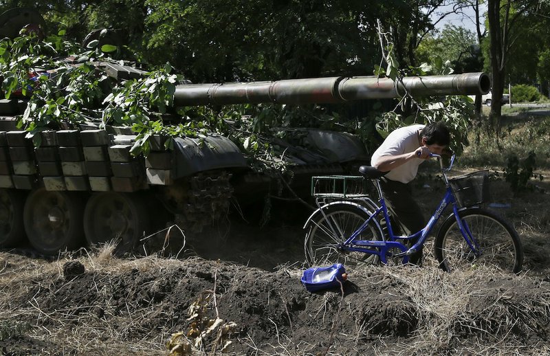 A resident passes by a cannon of a pro-Russian tank in the town of Novoazovsk in eastern Ukraine on Friday, Aug. 29, 2014. In Novoazovsk, pro Russian rebel fighters looked to be in firm control, well-equipped and relaxed. At least half a dozen tanks were seen on roads around the town, although the total number at the rebels’ disposal is believed to be much greater. Novoazovsk fell swiftly to the rebels Wednesday after being pounded by shelling.