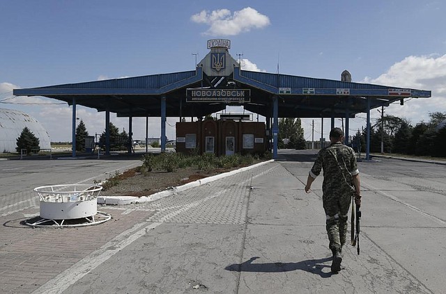 A pro-Russia rebel patrols at the Novoazovsk border crossing Friday in eastern Ukraine. Rebel fi ghters looked to be in control of the area, where at least a half-dozen tanks were seen on roads around the town.