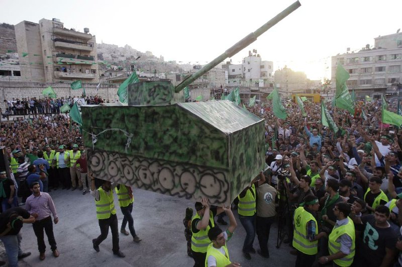 Palestinians carry a  mock Israeli tank during a celebration organized by Hamas in the West Bank city of Nablus, on Friday, Aug. 29, 2014.  Israel and Hamas militants fought for 50 days before reaching a truce on Tuesday.  Palestinian President Mahmoud Abbas has accused Hamas of needlessly extending fighting in the Gaza Strip, causing a high death toll. (AP Photo/Nasser Ishtayeh)
