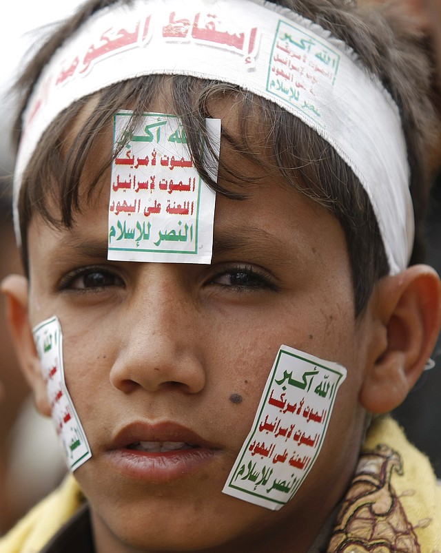 A Yemeni boy wearing a headband with Arabic writing reads,"Down with the government of corruption." and posters on his face reads,"Allah is the greatest. Death to America. Death to Israel. A curse on the Jews. Victory to Islam." attends a demonstration demanding the government to step down in Sanaa, Yemen, Friday, Aug. 29, 2014. Hundreds of thousands of Yemenis rallied in the capital and across the country against an armed Shiite rebel group which has been holding its own sit-in demanding a new government and the reinstatement of fuel subsidies.