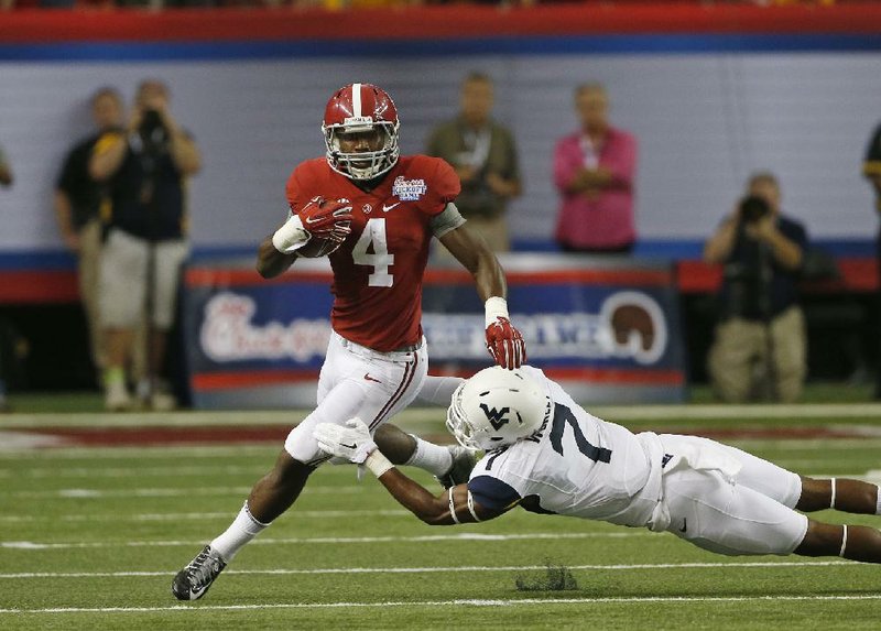 Alabama running back T.J.Yeldon (left) runs past West Virginia defensive back Daryl Worley during Saturday’s game at the Georgia Dome in Atlanta. Yeldon carried 23 times for 126 yards and 2 touchdowns in the Crimson Tide’s 33-23 victory.