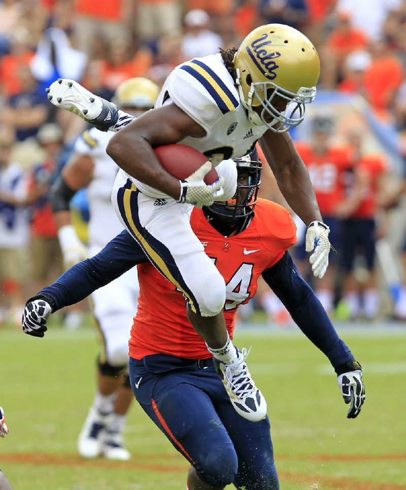 UCLA running back Nate Starks (23) leaps over Virginia linebacker Henry Coley (44) during the second half of the No. 7 Bruins’ 28-20 victory over the Cavaliers on Saturday in Charlottesville, Va.