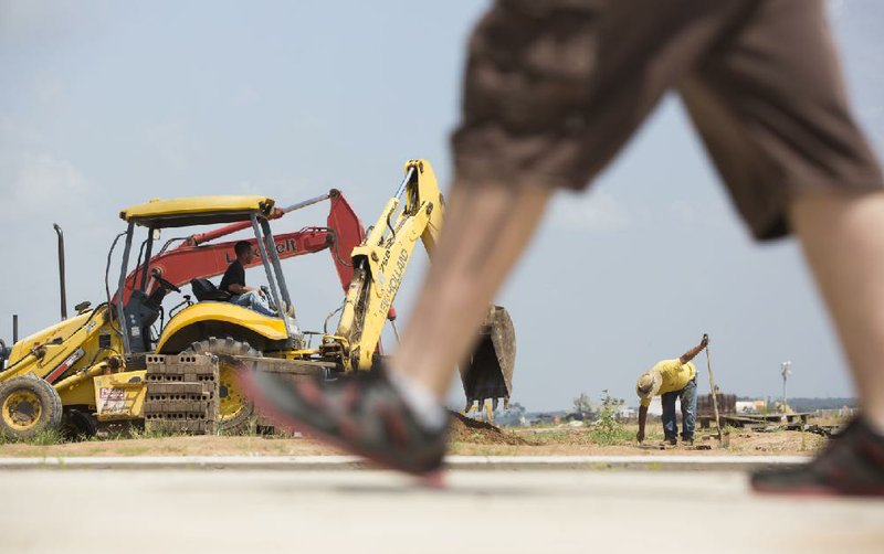 Danny Lindler works a backhoe recently under the direction of Aaron Gomez as they search for electrical lines at the new airport in Conway.