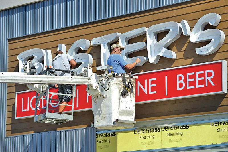 STAFF PHOTO BEN GOFF &#8226; @NWABenGoff Steve Harvey, left, and Lew Indorf, both with Ken&#8217;s Signs in Springdale, work Thursday on a new sign for Buster&#8217;s Liquor on West Walnut Street in Rogers. Renovation of the former Blockbuster Video location is under way, including installing of a large walk-in beer cave. The new business should open its doors in coming weeks.