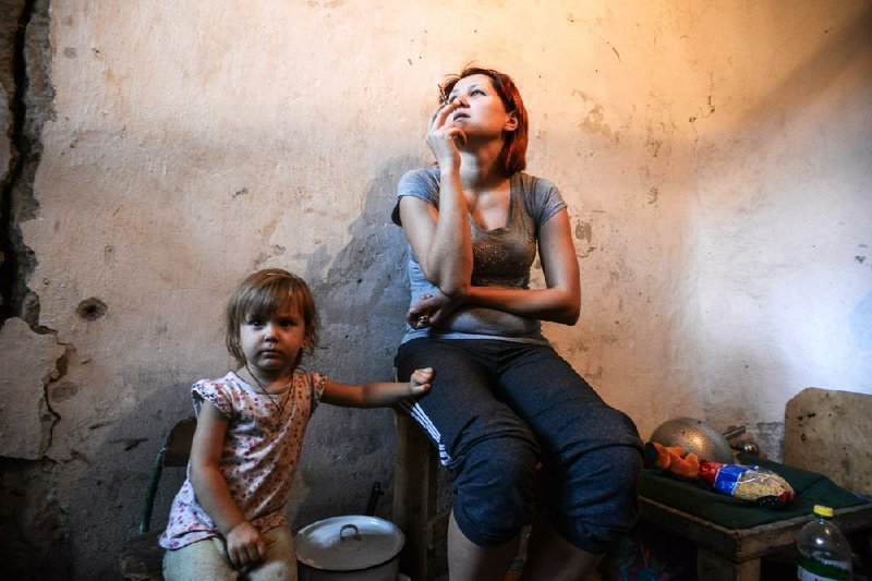 A mother and child hide in a bomb shelter in Petrovskiy district in Donetsk, eastern Ukraine, Monday, Sept. 1, 2014. The Petrovskiy district of Donetsk is currently a frontline and one of the districts which suffered the most from the artillery fights between Ukrainian army and Pro-Pussian rebels. (AP Photo/Mstislav Chernov)