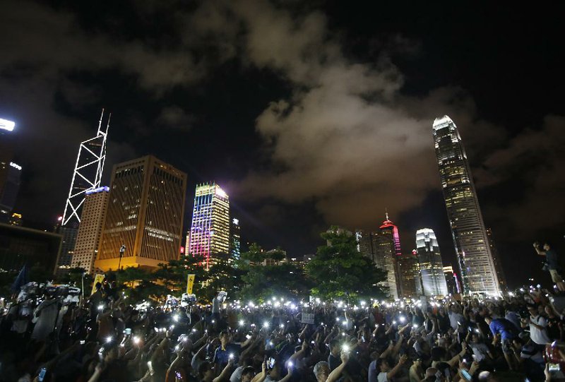 Protesters wave their mobile phones during a rally, after China's legislature has ruled out open nominations in elections for Hong Kong's leader in Hong Kong, Sunday, Aug. 31, 2014. China's legislature's standing committee announced Sunday that all candidates must receive more than half of votes from a special nominating body before going before voters. (AP Photo/Vincent Yu)