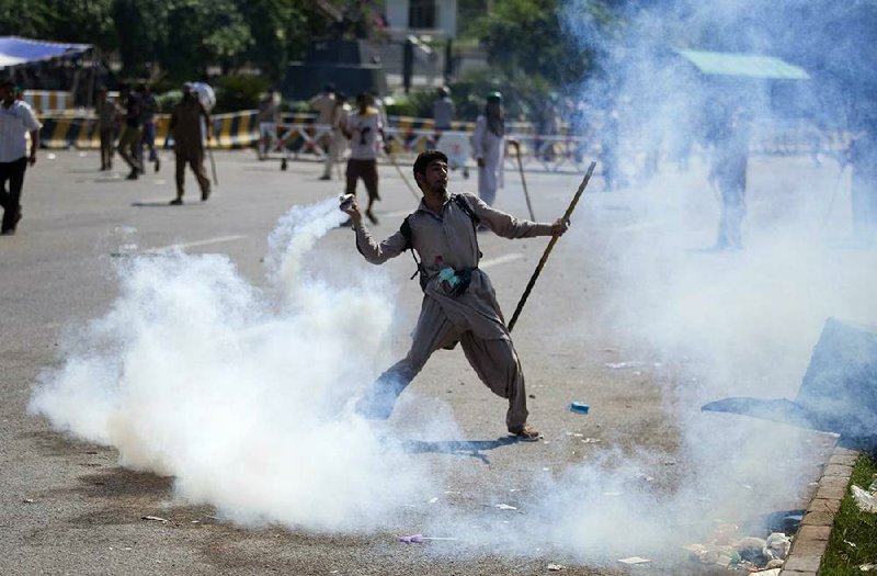 A Pakistani protester throws tear gas shell back towards police during a protest in Islamabad, Pakistan, Sunday, Aug. 31, 2014. Pakistani police clash with scattered pockets of anti-government protesters trying to advance on the prime minister’s residence after a night of violence that saw hundreds wounded and the first death Sunday in more than two weeks of demonstrations. (AP Photo/B.K. Bangash)