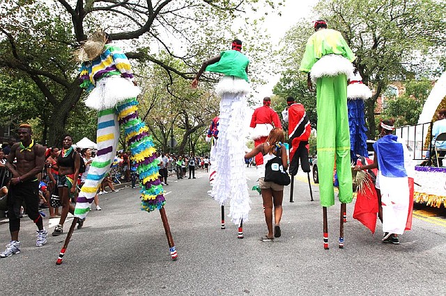 Parade participants on stilts and others make their way along Eastern Parkway in the Brooklyn borough of New York during the West Indian Day Parade, Monday, Sept. 1, 2014. (AP Photo/Tina Fineberg)