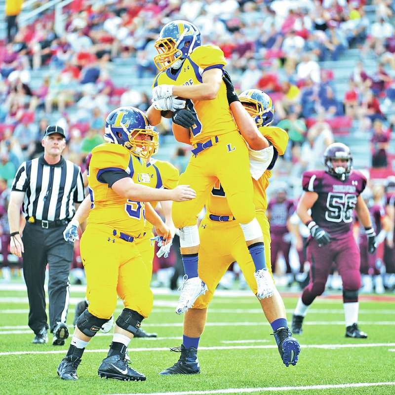 STAFF PHOTO ANDY SHUPE Hot Springs Lakeside receiver Cody Cockrell, top, celebrates Monday with teammates after scoring a touchdown against Lincoln during the first half at Razorback Stadium in Fayetteville.