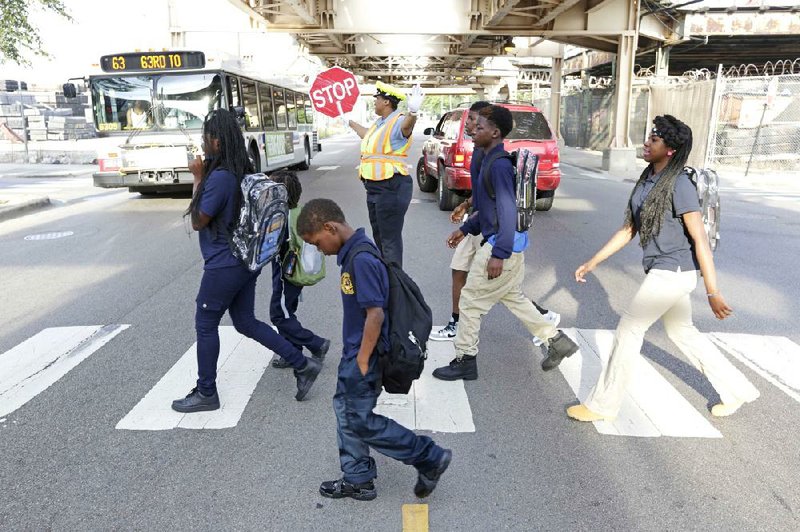 Schoolchildren walk a safe passage route Tuesday in Chicago as crossing guard Patricia Howard stops traffic for them.