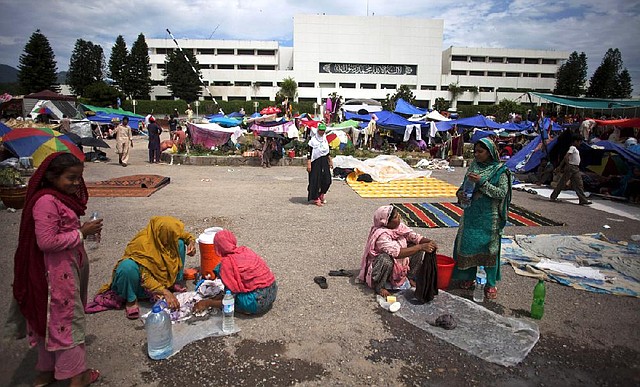 People do their laundry Tuesday at a camp in front of Pakistan’s parliament building in Islamabad where protesters have rallied for weeks seeking the prime minister’s resignation.