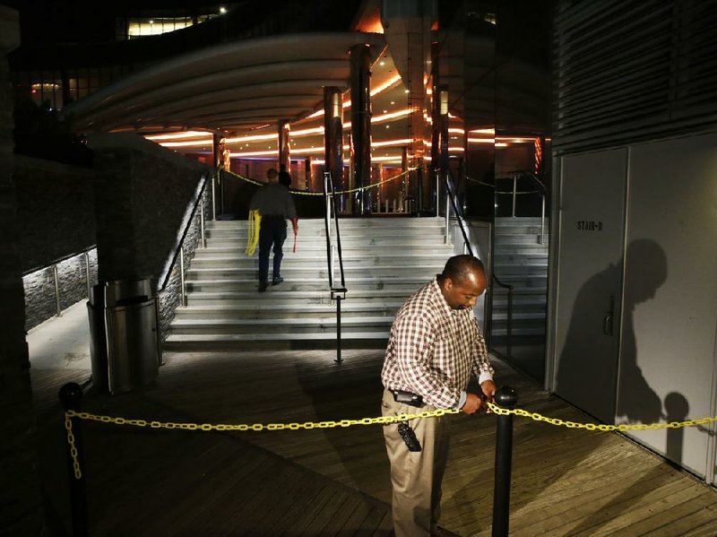 A casino worker secures a plastic chain across The Boardwalk entrance to the Revel Casino Hotel early Tuesday in Atlantic City, N.J.