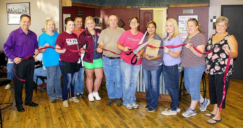 Cutting the ribbon at her new Gentry restaurant on Thursday (right) is Mary Varner (center) with her husband Keven. Helping her celebrate the event were Gentry mayor Kevin Johnston, Gentry Chamber of Commerce president Tammie Runyan, Brittany Nepomuceno, Lisa Crawford, Sydney Hodges, Gabby Hernandez, Jaime Pierce, Shawn Hunter and Chamber executive director Bev Saunders.