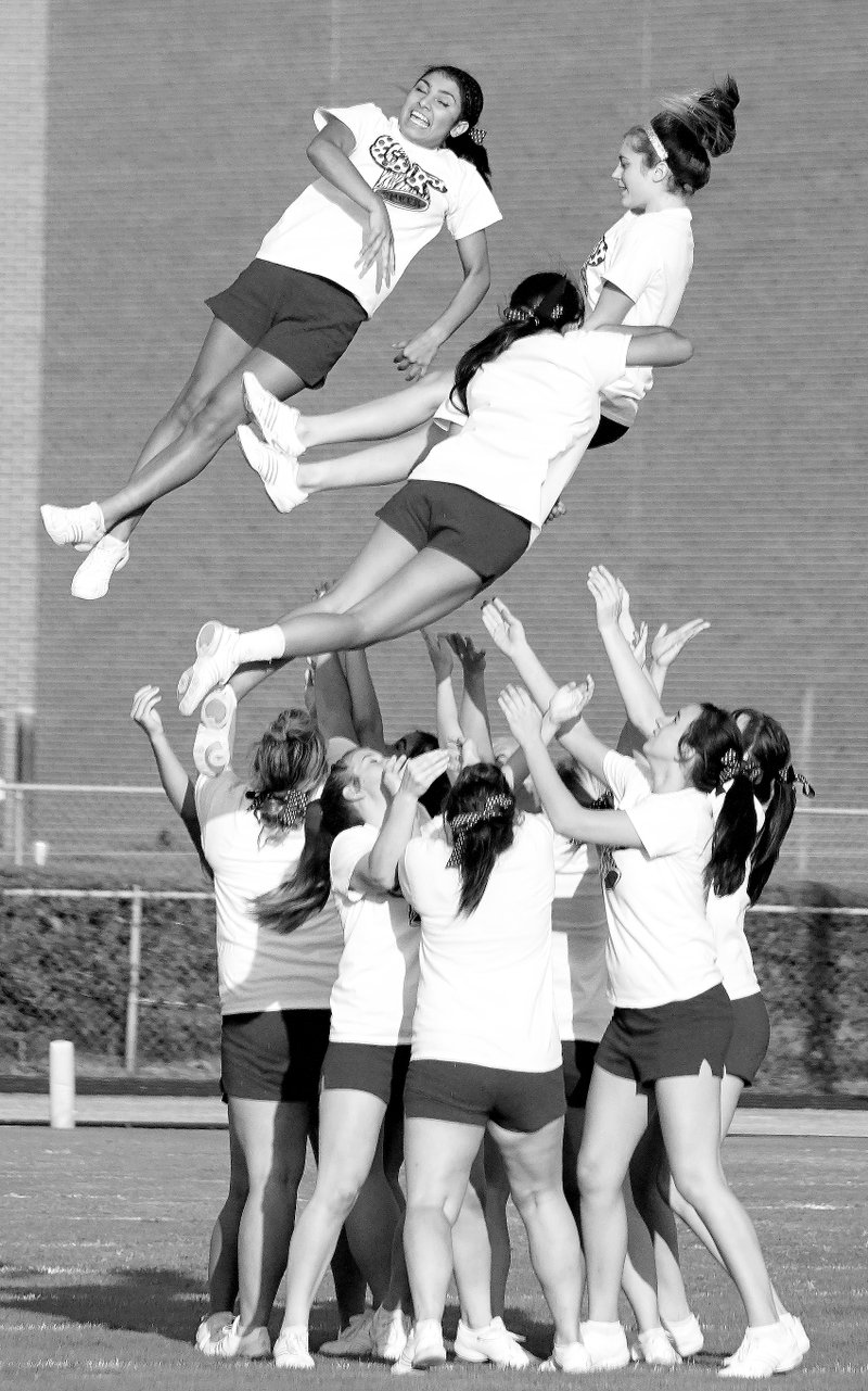 Photo by Randy Moll Gentry High School cheerleaders are tossed airborne for their teammates to catch during a halftime routine at the scrimmage game between Gentry and Decatur on Thursday.
