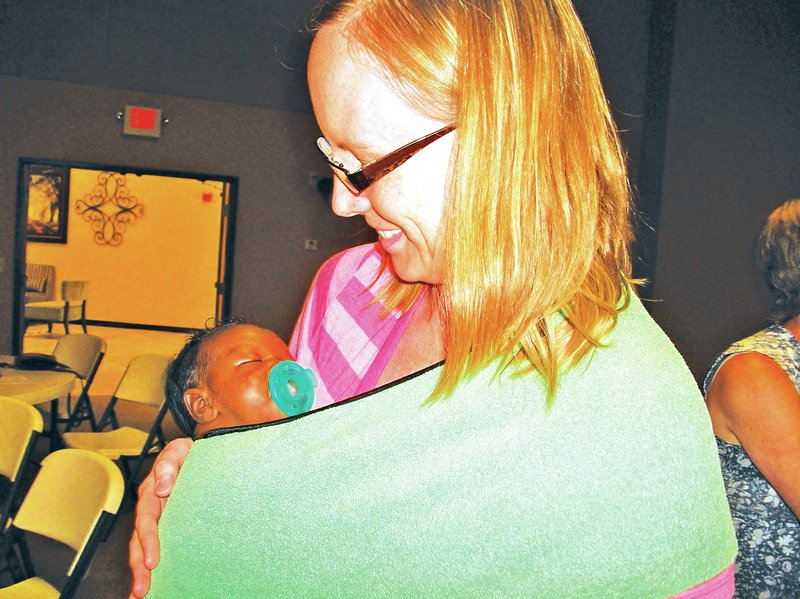 Staff Photo Becca Martin-Brown Chelsea Rustad is a big fan of baby wearing and recommends a pouch like this one as the easiest way to start. Her son, the youngest of children 9, 8, 5 and 3 at 6 weeks, sleeps comfortably as she explains the pouch to women at a discussion Saturday at Bella Vista Assembly of God Church.