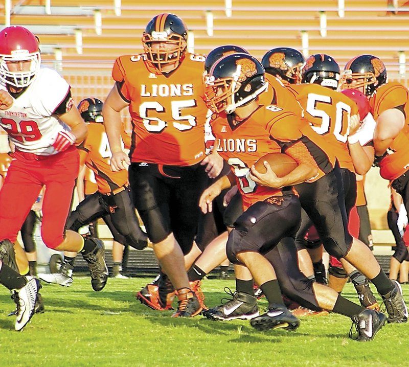 Gravette senior Brandon Holloway carries the ball past the line in scrimmage play against Farmington on Aug. 26 at Lion Stadium. Photos by Randy Moll