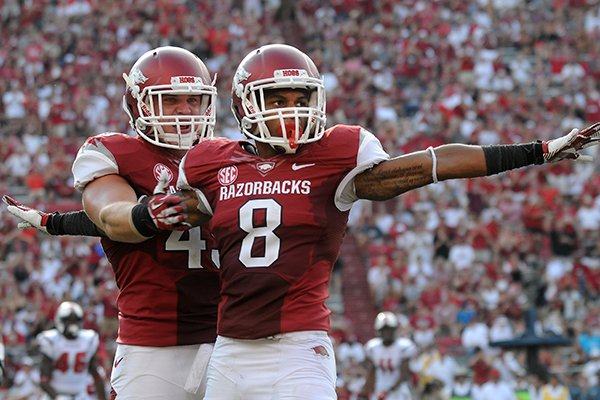 Austin Jones, left, hugs Tevin Mitchel Saturday, Aug. 31, 2013 after a tackle during the third quarter of the game against Louisiana-Lafayette at Razorback Stadium in Fayetteville.