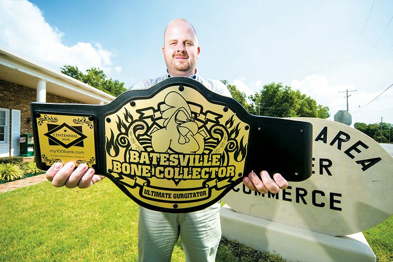 Adam Cartwright is coordinator of the The Bone Collector wing-eating competition, a fun aspect of the upcoming White River Carnival. He shows the belt that holds a plaque with the winner’s name engraved that will be on display at the Batesville Area of Commerce.
