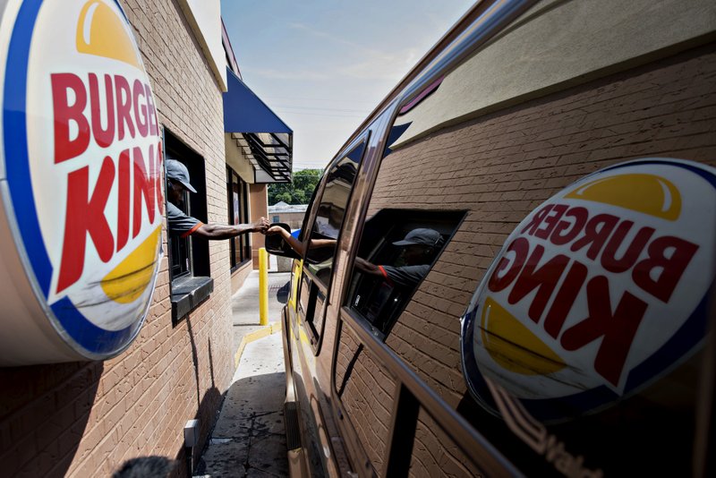 A Burger King employee assists a customer in 2014 at a restaurant in Peoria, Ill. 