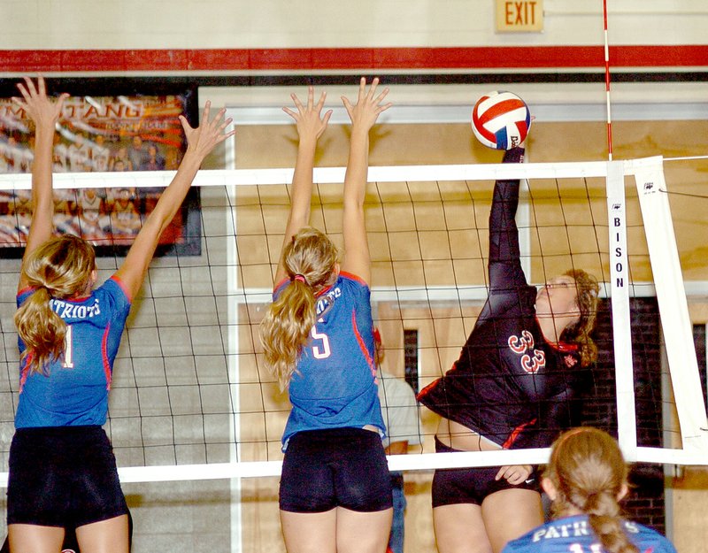 RICK PECK MCDONALD COUNTY PRESS McDonald County&#8217;s Lindsey Limore hits a spike past East Newton&#8217;s Aubrey McDermott (1) and Bethany Moorehouse during the Lady Patriots win Aug. 28 at MCHS.