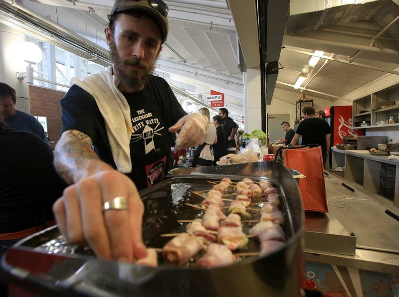White Water Tavern chef Michael Campbell cooks bacon-wrapped stuffed peppers for the 2013 Rock Town Bacon Throwdown at War Memorial Stadium.
