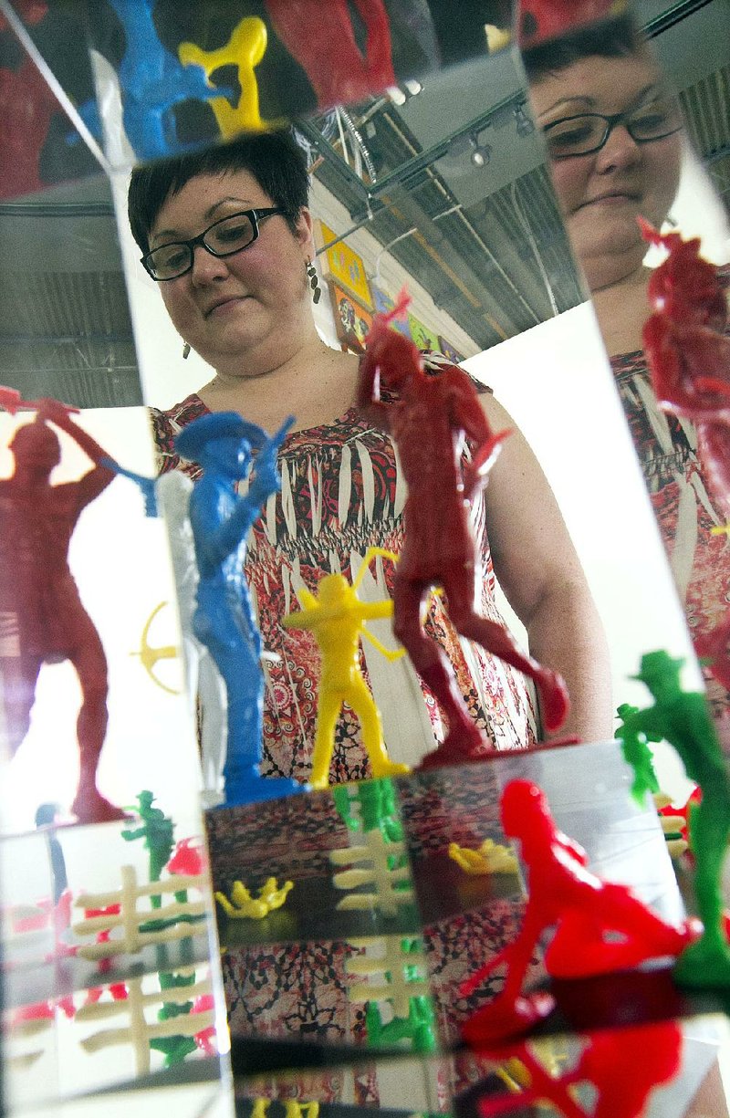 Erin Fehr, an archivist at the Sequoyah National Research Center in Little Rock, sets up cowboy and Indian toy figures in the center’s new exhibit, Toy Tipis and Totem Poles: Native American Stereotypes in the Lives of Children.