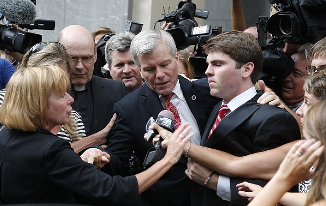 Former Virginia Gov. Bob McDonnell (center) is mobbed by media as he gets into a car with his son, Bobby (right), after he and his wife, former first lady Maureen McDonnell, were convicted on multiple counts of corruption at federal court in Richmond, Va., on Thursday.
