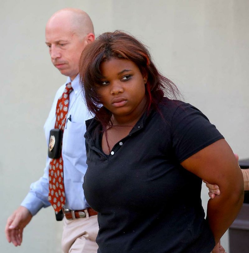 Little Rock police detective Grant Humphries leads Ryeisha Gaines, 18, away from the Little Rock police station on West Markham Street on Thursday after she was charged with aggravated assault.