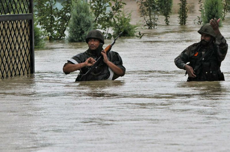 Indian army soldiers walk through a flooded road during a rescue operation in Srinagar, India, Thursday, Sept. 4, 2014. At least 100 villages across the Kashmir valley were flooded by overflowing lakes and rivers, in the worst flooding in 22 years caused by heavy rains. (AP Photo/Mukhtar Khan)