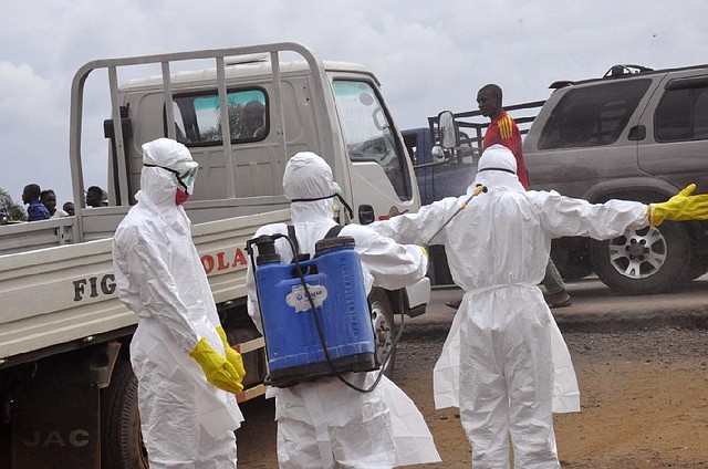 Health worker's spray each other with disinfectant chemicals as they worked with a suspected  Ebola virus death in Monrovia, Liberia, Thursday, Sept. 4, 2014. As West Africa struggles to contain the biggest ever outbreak of Ebola, some experts say an unusual but simple treatment might help: the blood of survivors. The evidence is mixed for using infection-fighting antibodies from survivors' blood for Ebola, but without any licensed drugs or vaccines for the deadly disease, some say it's worth a shot. (AP Photo/Abbas Dulleh)