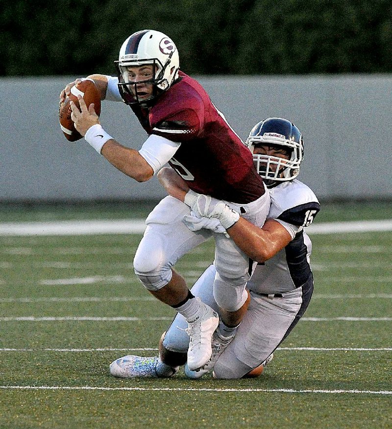 Springdale quarterback Fuller Chandler is dragged down by Greenwood’s Morgan Grant during the first half.