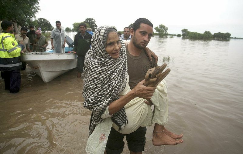 A Pakistani rescue worker carries an elderly woman from an area flooded by rain in Sodran village, some 100 kilometers (65 miles) north of Lahore, Pakistan, Saturday, Sept. 6, 2014. Heavy monsoon rains and flash floods have killed more than 100 people in Pakistan officials said Saturday, as forecasters warned of more rain in the coming days and troops raced to evacuate people from deluged areas. (AP Photo/K.M. Chaudary)