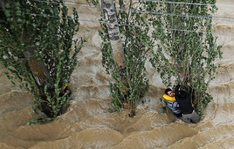 Kashmiris caught in high water cling to a tree Tuesday in Srinagar, India, as monsoon flooding continues to sweep across parts of India and Pakistan. More than 440 people have been killed, and as helicopters and boats raced to rescue the marooned, authorities warned that hundreds of thousands of people should be prepared to •ee their homes.