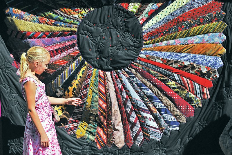 File Photo Raevin Allen of Goshen looks at a tie quilt on display last year during the Ozark Quilt Fair at the Shiloh Museum in Springdale. The 37th annual event, which includes a variety of handmade quilts from local quilt makers, an indoor quilt exhibit by the Itty Bitty Quilt Committee and live music by Working Class Grass, is Saturday at the museum.