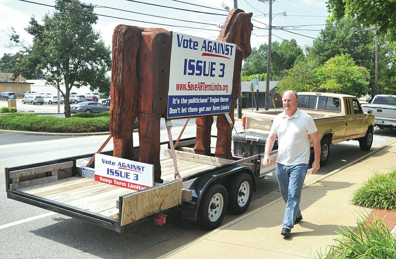 STAFF PHOTO Michael Woods &#8226; @NWAMICHAELW Bob Porto walks Tuesday past his 10-foot trojan horse on the back of his trailer parked in front of the Shiloh Museum of Ozark History in Springdale as he heads to a news conference. Porto is trying to educate voters on the effects of Referred Issue 3 about term limits in Arkansas.