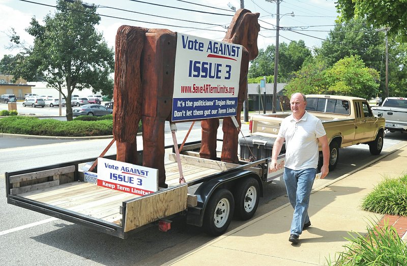 STAFF PHOTO Michael Woods &#8226; @NWAMICHAELW Bob Porto walks Tuesday past his 10-foot trojan horse on the back of his trailer parked in front of the Shiloh Museum of Ozark History in Springdale as he heads to a news conference. Porto is trying to educate voters on the effects of Issue 3 about term limits in Arkansas.