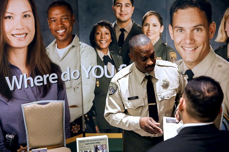 A California Department of Corrections and Rehabilitation officer speaks with a job seeker at the Career Choice Inland Empire Career Fair in Ontario, California, U.S., on Wednesday, Sept. 10, 2014. The U.S. Department of Labor is scheduled to release intial jobless claims figures on Sept. 11, 2014. Photographer: Patrick T. Fallon/Bloomberg