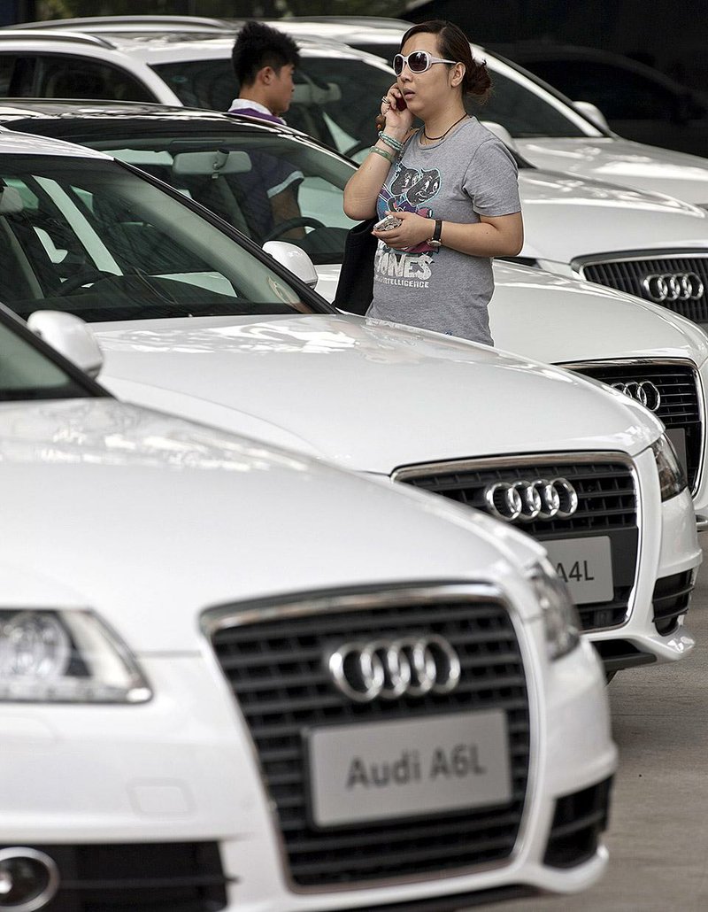 FILE - In this August 4, 2011 file photo, visitors look at Audi's models on display outside a shopping mall during a road show in Beijing, China. China on Thursday, Sept. 11, 2014, announced it will fine automaker Audi $40.5 million and Chrysler $5.2 million in a sweeping anti-monopoly probe of their industry that has prompted complaints foreign businesses are being treated unfairly. (AP Photo/Andy Wong, File)