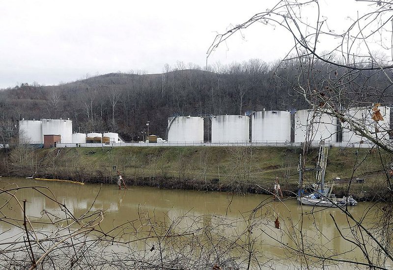 FILE - In this Jan. 13, 2014 file photo, workers, left, inspect an area outside a retaining wall around storage tanks where a chemical leaked into the Elk River at Freedom Industries storage facility in Charleston, W.Va. The powerful chemical industry is putting its lobbying muscle behind legislation that would establish standards for chemicals used in products from household goods to cellphones and plastic water bottles _ but also make it tougher for states to regulate them.   (AP Photo/Steve Helber, File)