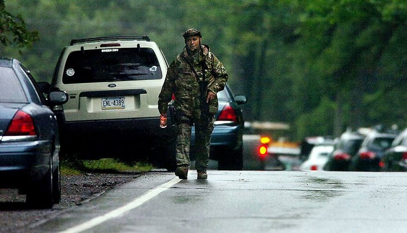 A member of the Pennsylvania State Trooper's Tactical Response Unit, walks along Route 402 on Saturday, Sept. 13, 2014, near the scene where a Pennsylvania State Trooper was killed and another trooper was injured during a shooting late Friday night at the Pennsylvania State Police barracks in Blooming Grove Township, Pennsylvania.  (AP Photo/The Scranton Times-Tribune, Butch Comegys)